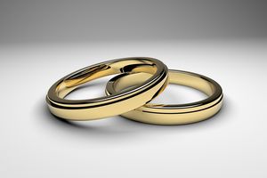 2 goldene Eheringe. Ein Ring liegt zum Teil auf dem anderen Ring.