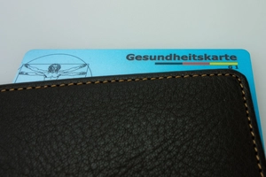 Krankenversicherungskarte schaut aus einer schwarzen Geldbörse hervor.
